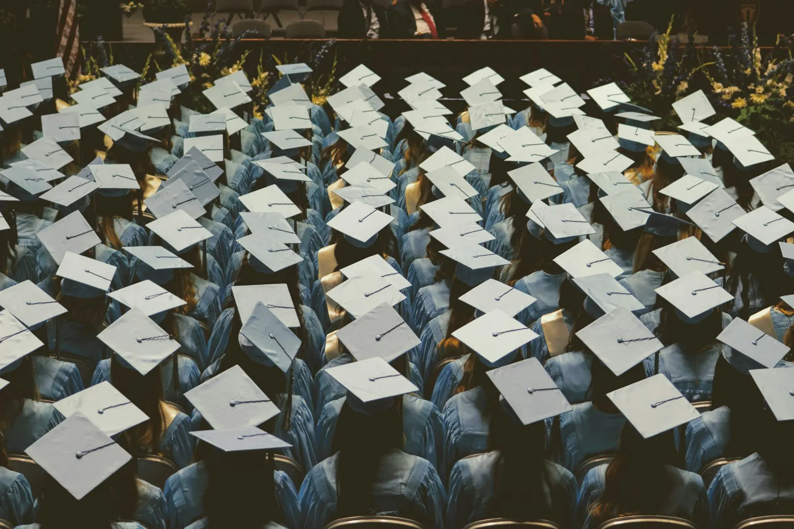 Graduates in light blue gowns and caps seen from above at a ceremony