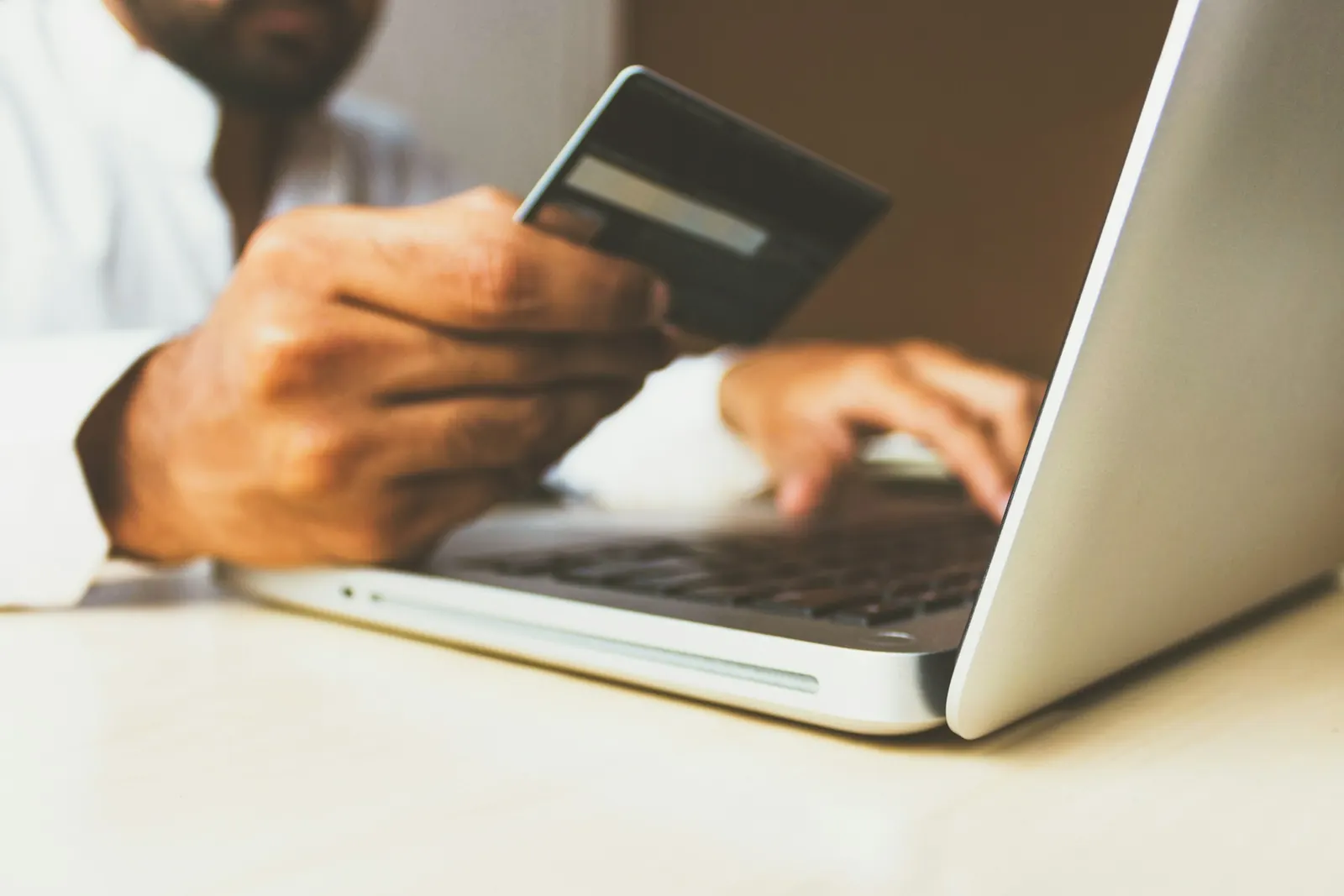 Person holding a bank card in front of a laptop