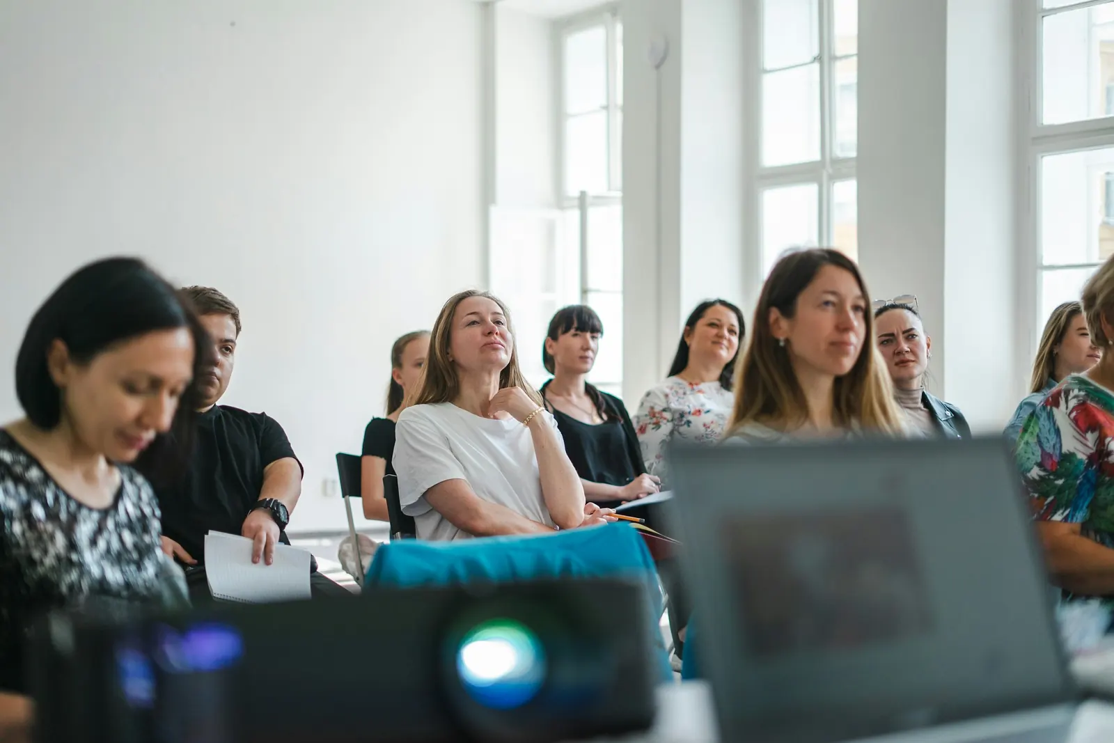 Studierende sitzen in einem hellen Seminarraum und hören zu